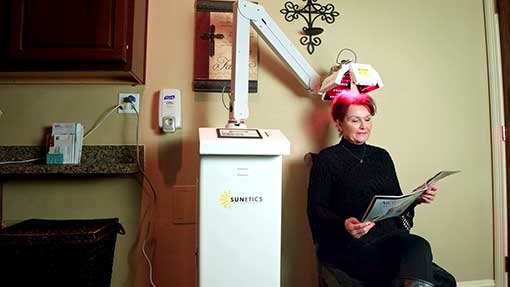 woman is sitting under a laser reading a magazine with no pain